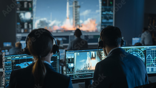 Group of People in Mission Control Center Witness Successful Space Rocket Launch. Flight Control Employees Sit in Front Computer Displays and Monitor the Crewed Mission.