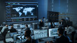 © Gorodenkoff - Shot of Officers in a Surveillance Control Center with Police Global Map Tracking on a Big Digital Screen. Monitoring Room Employees Sit in Front of Computer Displays and Analyze Big Data.