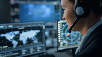 Fototapete - Computer Screen with Global Map Technology Used by a Female Flight Controller in a Mission Control Center Room with Other Scientists. Team of Engineers Work in Monitoring Room Full of Displays.