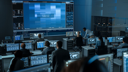 group of people in mission control center trying to establish video connection on a big screen with 