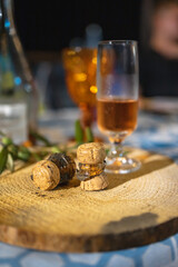 Glass of champagne with two broken corks lay on wooden board on table