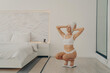 © VK Studio - Beautiful young fit female model squats on scales in modern bedroom interior