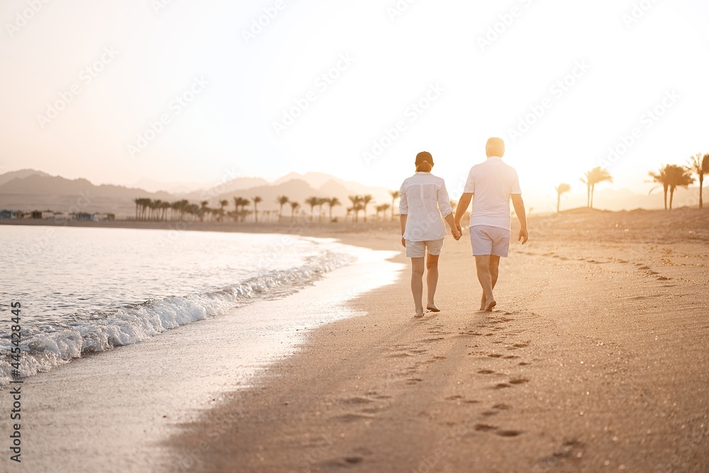 Happy mature senior couple walking and looking at each other on beach ...