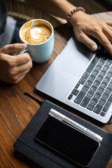 Young man using laptop in cafe near sea, freelance work, outdoor hipster portrait, smartphone, paradise island, Bali, Thailand, network, headphones, phone, breakfast at work, coffee in hand, earphones