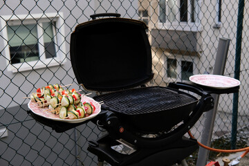 Wall Mural - Closeup shot of seasoned vegetables on skewers on a plate near a grill