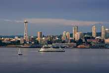 A Sailboat And Washington State Ferry Boat Sail On Puget Sound As The Famous Space Needle And Skyscrapers Rise Above Elliott Bay In Seattle.