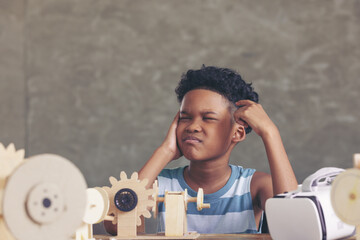 Wall Mural - African black boy thinking contemplating design and looking out above and having the simulation mechanism robot model wooden on table in classroom.