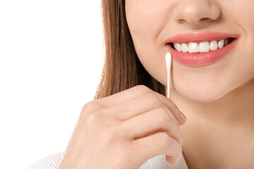 Wall Mural - Young woman with cotton bud on white background, closeup