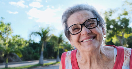 Smiling old Latin woman. Beautiful senior woman looking at the camera with a warm friendly smile and attentive expression. Elderly woman laughing.