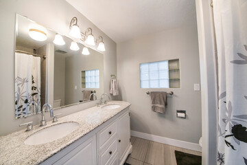 Interior of a bathroom with double vanity sink and a window with glass cube panel