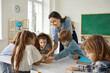 © Studio Romantic - Happy school teacher and students having interesting class in modern classroom. Little children reading book, looking at pictures, learning, discussing new things, working on creative project together