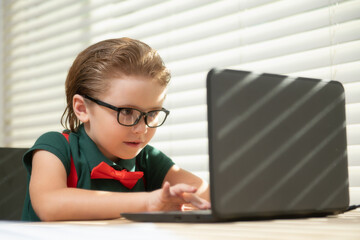 Preteen schoolboy doing her homework with laptop at home. Online education concept, home schooler pupil.