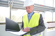 © kittyfly - experienced elderly builder, construction team leader, construction engineer in white helmet protection signs documents at construction site for building renovation, civil engineering concept