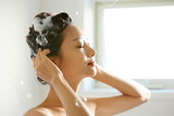 バスルームで髪の毛のシャンプーをする若い女性