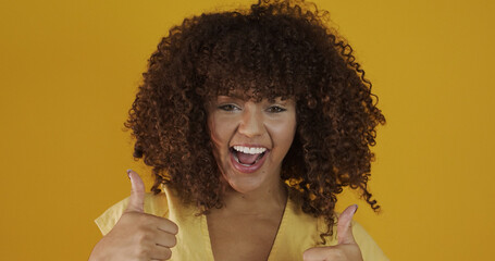 Wall Mural - Beautiful brunette model smiling at camera. Beautiful teeth. Curly hair. Brazilian young woman. Thumbs up.