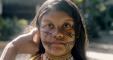 Young Brazilian girl indigenous Pataxó ethnicity doing face painting.