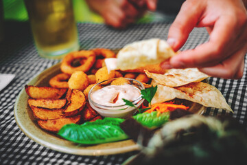 Canvas Print - man hand and plate with snacks on table background on bar or pub