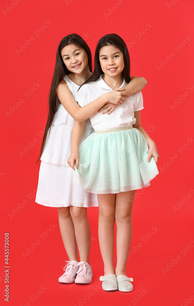 Cute Asian sisters on color background