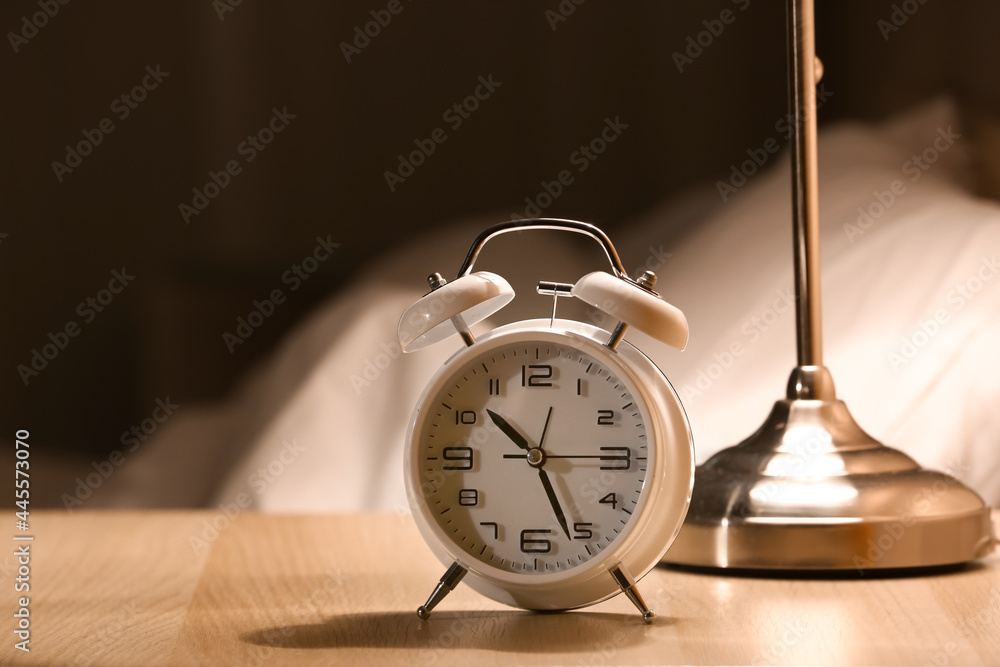 Alarm clock on table in bedroom at night, closeup