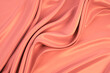 Beautiful elegant wavy coral satin silk luxury cloth fabric texture with monochrome background design. Copy space