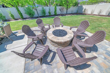Backyard Fire Pit Made Of Brick On The Deck Of A Home With Chairs Set Up Around It