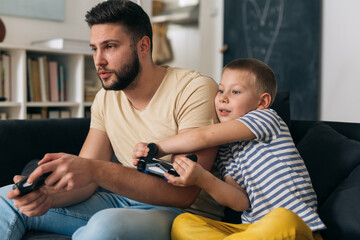 Wall Mural - father and son playing video games with controllers at home