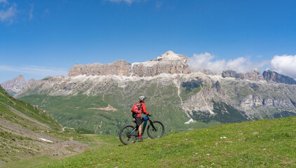 Wall Mural - pretty active senior woman riding the famous Sella Ronda  mountain bike Trail  in Sella mountain group, Dolomites  of Selva Wolkenstein, Val Gardena, South Tirol and Trentino, Italy