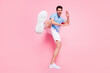 Full length body size photo smiling man in blue shirt practising karate isolated pastel pink color background