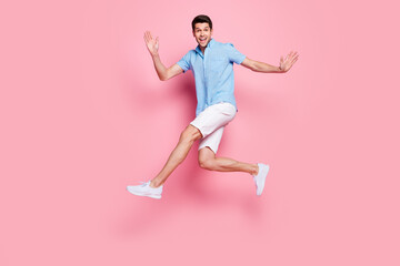 Wall Mural - Photo of careless athletic man jump run enjoy summer holiday wear blue shirt shorts shoes isolated on pink color background