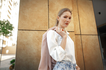 Sticker - Stylish girl in jeans and white cotton blouse posing near gray wall