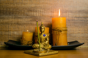 Closeup shot of a small statue with a candle on a wooden background