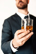 Business professional in suit holding up a rocks glass cocktail drink.