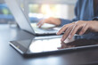 © tippapatt - Close up of woman hand using digital tablet, finger touching on screen and working on laptop computer on table at home office