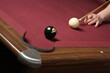 pool player lining up cue and eight ball ready to shoot winning shot into billiard pocket