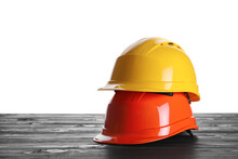 Different Hard Hats On Wooden Table Against White Background. Space For Text