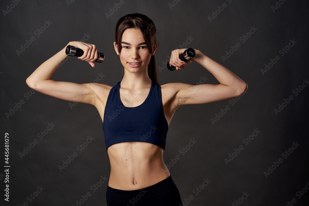 athletic woman slim figure dumbbells in the hands of fitness pumped up muscles - obrazy, fototapety, plakaty 