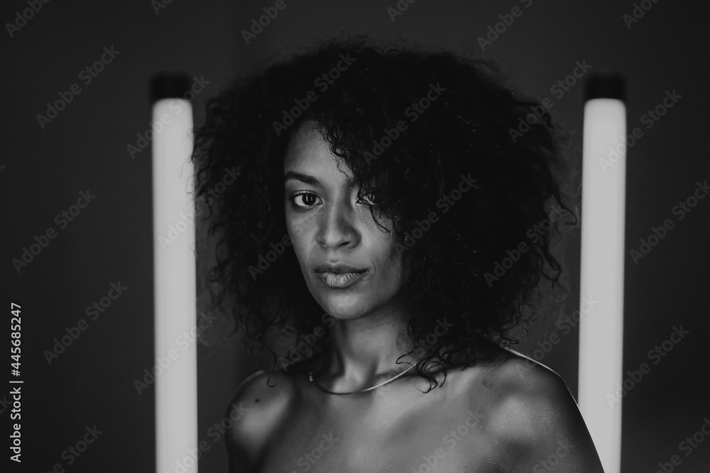 Mixed race nude woman with curly african hair on dark background. Black