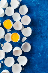 Wall Mural - there are many white eggshells on a blue background. in two shells there is a yolk from an egg