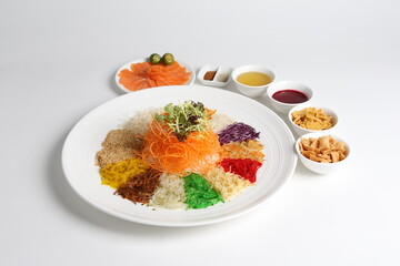 chinese new year colourful lo hei yu sheng with smoked salmon, vegetables and sauces in white gold background asian halal menu for cny festival