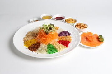 Wall Mural - chinese new year colourful lo hei yu sheng with smoked salmon, vegetables and sauces in white gold background asian halal menu for cny festival