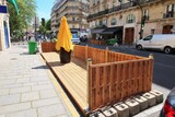 Fototapeta Tęcza - Terrasse éphémère estivale / extension de terrasse / contre-terrasse de café / bar / restaurant, en bois, vide, sur des places de stationnement le long d'un trottoir dans une rue de Paris (France)