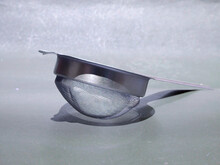 Aluminium Metal Tea Filter Kept On Gray Surface, Kitchen Cutlery Product Image.