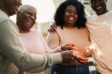 Wall Mural - Happy black family celebrating with sparklers outdoor at home - Focus on mother face