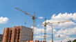 © eliosdnepr - Crane and workers at construction site against blue sky.