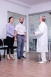 © DC Studio - Worried woman looking at doctor waiting for medical results holding husband hand, standing in reception of hospital clinic. Stressed young couple receiving unfavorable news in waiting area.