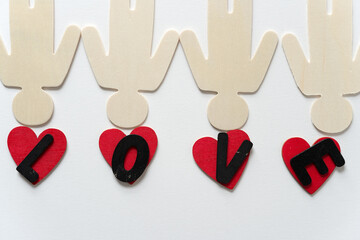 upside down flat wooden shapes (male) with hand painted red hearts and black chalk letters l, o, v, and e on a light background