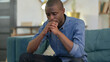 © stockbakers - Worried Young African Man Having Headache on Sofa