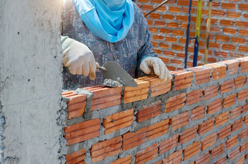 masonry worker make concrete wall by cement block and plaster at construction site