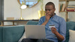© stockbakers - Fail Online Shopping by Young African Man on Sofa