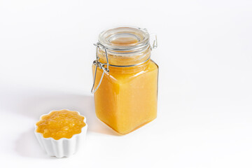 Wall Mural - Yellow jam on a white background. Fruit homemade confiture in a jar and a bowl close up. Copy space.